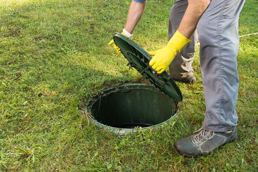 Hands opening septic tank lid