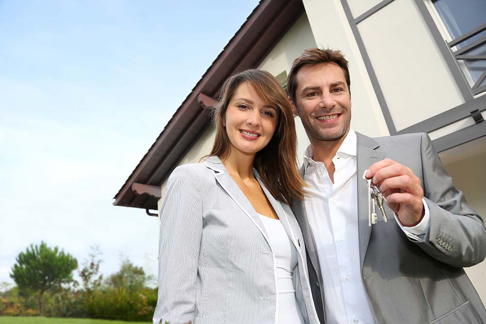 Couple holding the keys to their new house after it passed a thorough home inspection